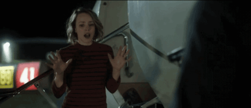 A Woman Standing In Front Of An Airplane With The Word Oh Written On The Bottom GIF