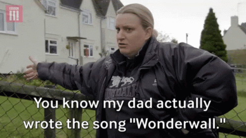 a woman standing next to a fence with the words " you know my dad actually wrote the song wonderwall "