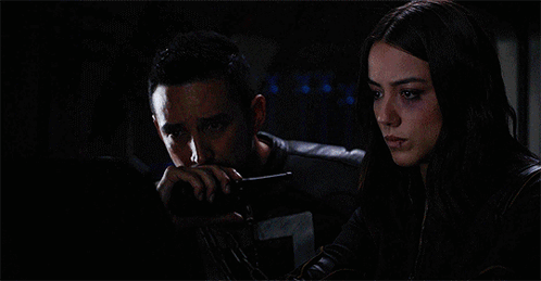 A Woman Standing Next To A Man Laying In A Bed With A Monitor Behind Them That Says A On It GIF
