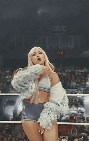 A Woman Stands In A Boxing Ring With The Number 116 On The Wall Behind Her GIF