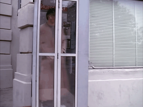 A Woman Stands In A Phone Booth With A Sign That Says ' Mura ' On It GIF