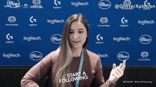 A Woman Stands In Front Of A Blue Background With Logitech And Blue Logos GIF