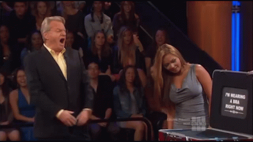 A Woman Stands In Front Of A Briefcase That Says ' I 'M Wearing A Bra Right Now ' On It GIF