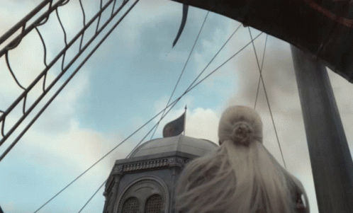 A Woman Stands In Front Of A Building With A Black Flag On Top GIF