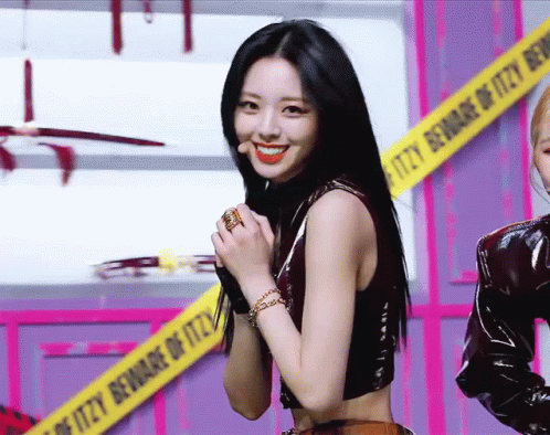 A Woman Stands In Front Of A Caution Tape That Says Itzy Beware Of Itzy GIF