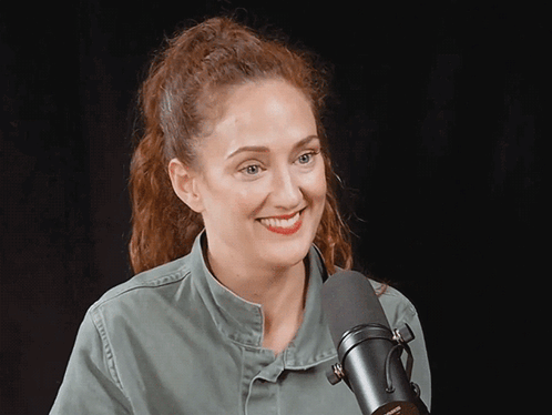 A Woman Stands In Front Of A Microphone That Says Shure GIF