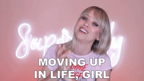 A Woman Stands In Front Of A Neon Sign That Says Moving Up In Life Girl GIF