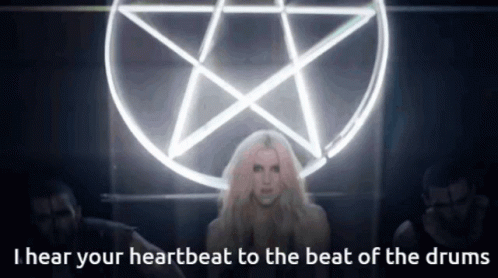 A Woman Stands In Front Of A Pentagram With The Words I Hear Your Heartbeat To The Beat Of The Drums GIF