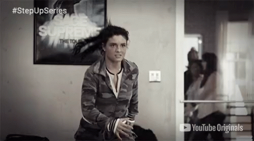 A Woman Stands In Front Of A Poster That Says " Supreme " GIF