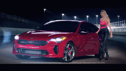 A Woman Stands In Front Of A Red Kia Stinger GIF