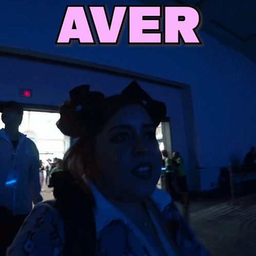 A Woman Stands In Front Of A Sign That Says " Aver " GIF