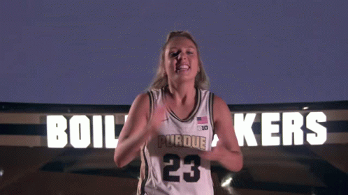 a woman stands in front of a sign that says ' boilermakers ' on it