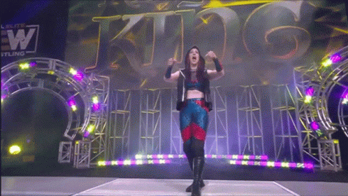 A Woman Stands In Front Of A Sign That Says King On It GIF