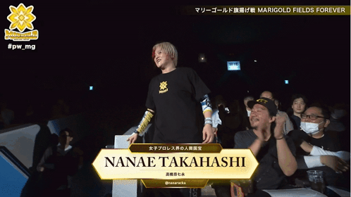 A Woman Stands In Front Of A Sign That Says Nanae Takahashi GIF