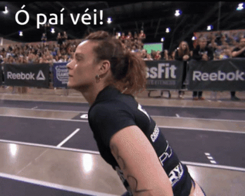 A Woman Stands In Front Of A Sign That Says Reebok On It GIF