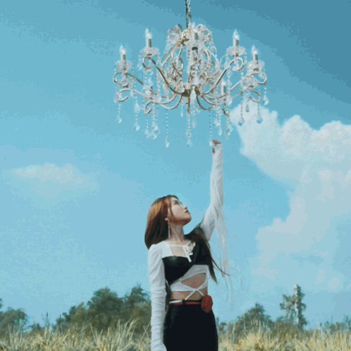 A Woman Stands In Front Of A Tree With Flowers And A Chandelier GIF
