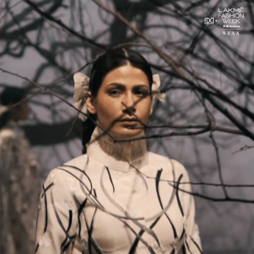 A Woman Stands In Front Of A Tree With The Words Lakme Fashion Week Next On The Bottom Right GIF