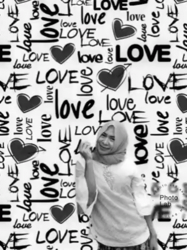 A Woman Stands In Front Of A Wall That Has The Word Love Written On It GIF