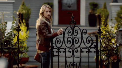 Woman Standing In Front Of Wrought Iron Gate GIF
