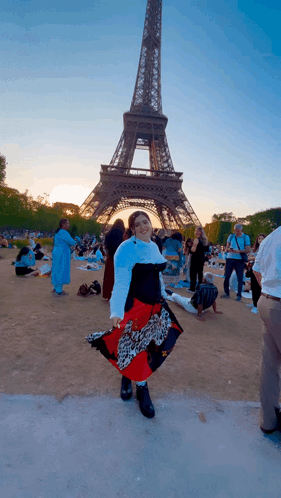 A Woman Stands In Front Of The Eiffel Tower Wearing A Leopard Print Skirt GIF