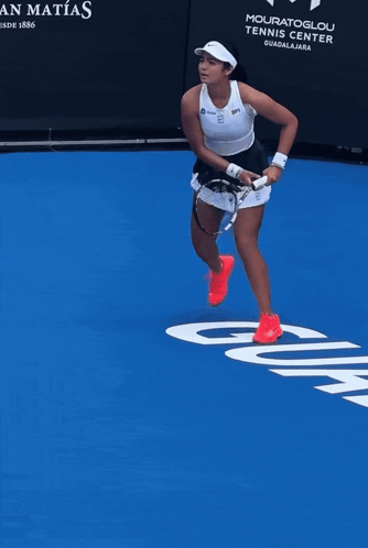 A Woman Stands On A Blue Tennis Court In Front Of A Sign That Says Casa San Matos GIF