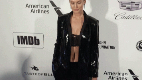 A Woman Stands On A Red Carpet In Front Of An Imdb Logo GIF