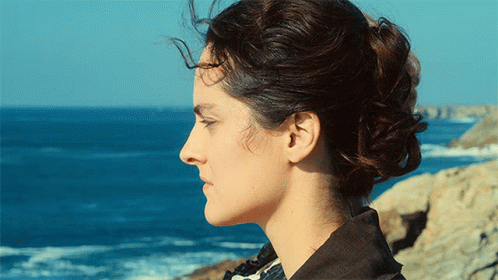 A Woman Stands On A Rock Near The Ocean GIF