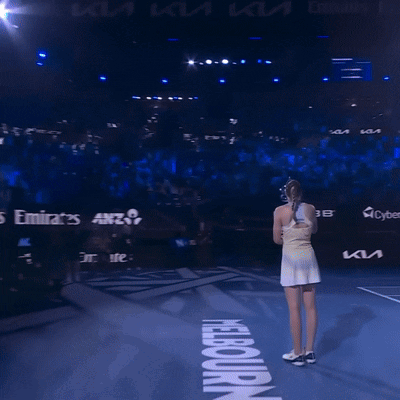 a woman stands on a tennis court in front of a sign that says ' nba ' on it