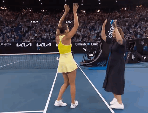 a woman stands on a tennis court with a sign that says emirates emir on it