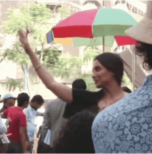 A Woman Stands Under A Colorful Umbrella In Front Of A Building With The Word Vad On It GIF