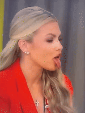 A Woman Sticking Her Tongue Out While Wearing A Cross Necklace GIF