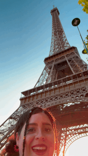 A Woman Taking A Picture In Front Of The Eiffel Tower GIF