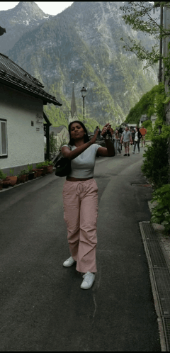 A Woman Taking A Picture Of A Mountain While Standing On A Street GIF