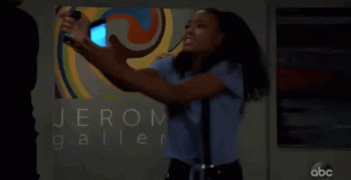 A Woman Taking A Picture Of Herself In Front Of A Sign That Says Jerom Galler GIF