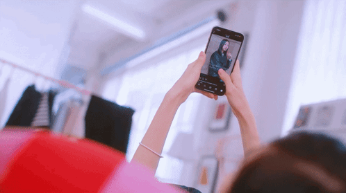 A Woman Taking A Picture Of Herself With A Cell Phone GIF
