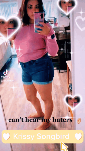 A Woman Taking A Selfie In Front Of A Mirror With Krissy Songbird In The Corner GIF
