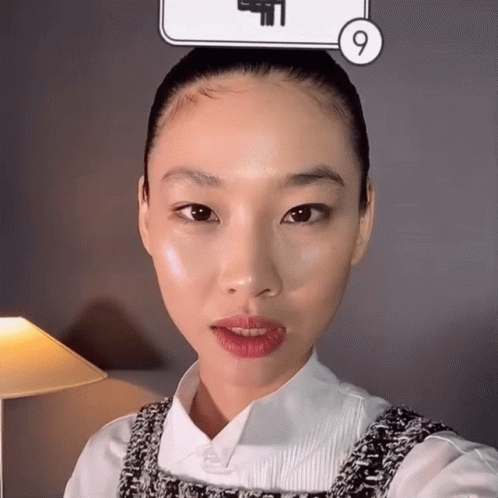 A Woman Taking A Selfie In Front Of A Sign That Has The Number 9 On It GIF