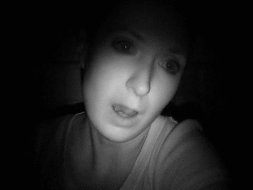 A Woman Taking A Selfie In The Dark With Her Eyes Closed GIF