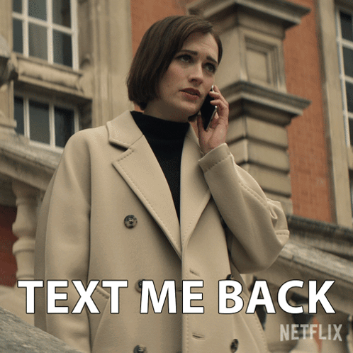 A Woman Talking On A Cell Phone Next To A Sign That Says Text Me Back Netflix GIF