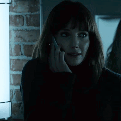A Woman Talking On A Cell Phone With A Brick Wall In The Background GIF