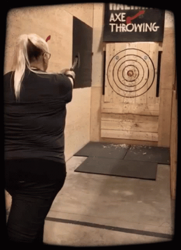 A Woman Throwing An Axe At A Target That Says Axe Throwing GIF