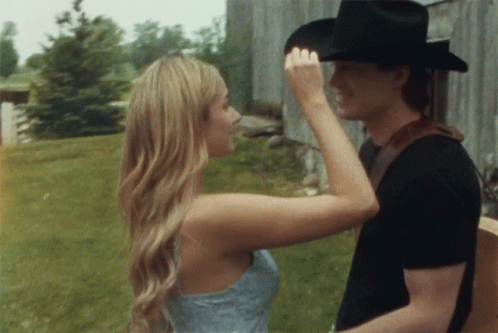 A Woman Touches A Man 'S Forehead While He Holds A Guitar GIF