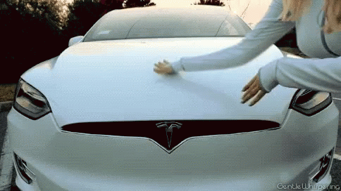 A Woman Touches The Hood Of A White Tesla GIF
