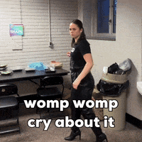 A Woman Walking In A Room With The Words Womp Womp Cry About It GIF