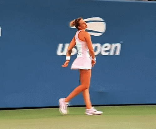 a woman walking on a tennis court in front of a wall that says open