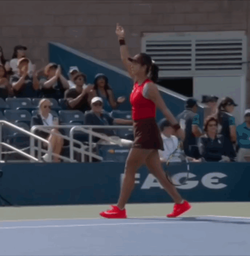 A Woman Walking On A Tennis Court With A Sign That Says Ace GIF