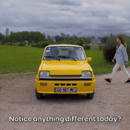 A Woman Walks Past A Yellow Car With The License Plate Go-967 Me GIF