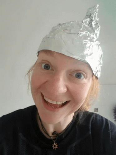 A Woman Wearing A Aluminum Foil Hat Smiles For The Camera GIF