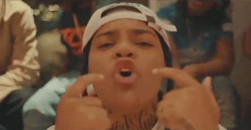 A Woman Wearing A Bandana And A Hat Is Making A Funny Face With Her Hands . GIF