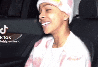 A Woman Wearing A Beanie Is Smiling In A Car With A Tiktok Logo In The Background GIF